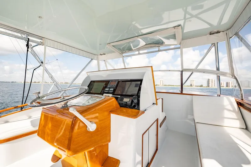 Slide: The Image of 1983 Rybovich 55 Convertible yacht helm with wooden steering and modern navigation. - 70