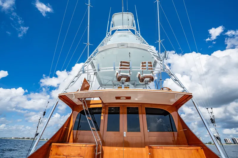 Slide: The Image of 1983 Rybovich 55 Convertible yacht with wooden finish against blue sky and clouds. - 81