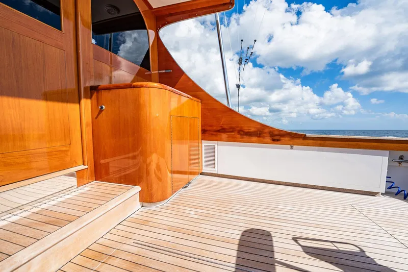 Slide: The Image of 1983 Rybovich 55 Convertible yacht deck with wooden finish, ocean view, and blue sky. - 84