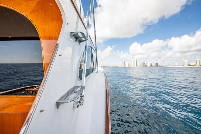 Slide: The Image of 1983 Rybovich 55 Convertible yacht cruising on open water with city skyline. - 85