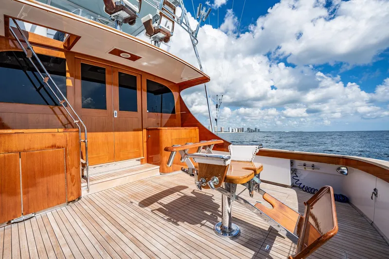 Slide: The Image of 1983 Rybovich 55 Convertible yacht deck with wooden finish, ocean view, and fishing chair. - 88