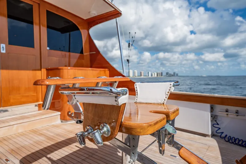 Slide: The Image of 1983 Rybovich 55 Convertible yacht deck with fishing chair, ocean view, and city skyline. - 89
