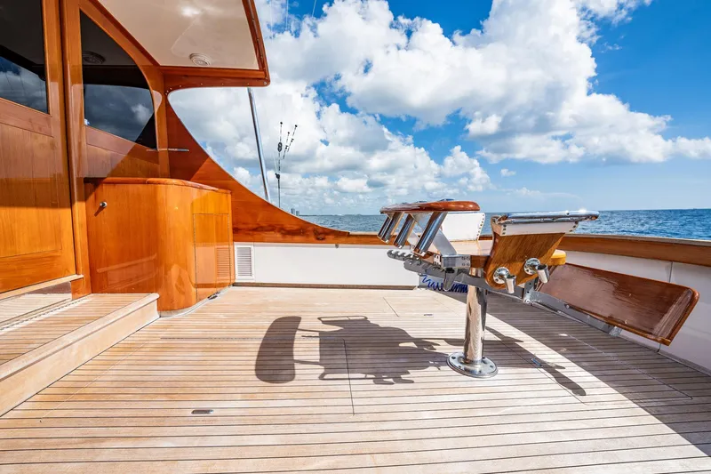 Slide: The Image of 1983 Rybovich 55 Convertible yacht deck with wooden finish, ocean view, and clear sky. - 90