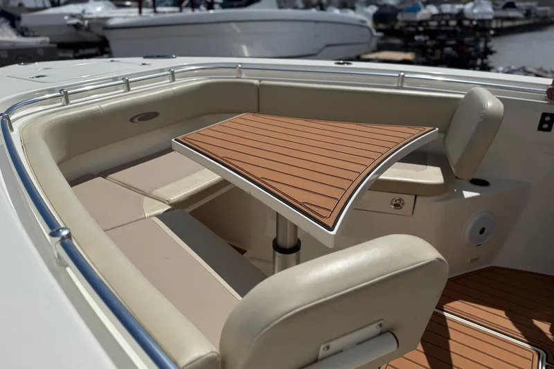 Slide: The Image of 2016 Cobia 277 Center Console boat with cushioned seating and wooden table. - 21