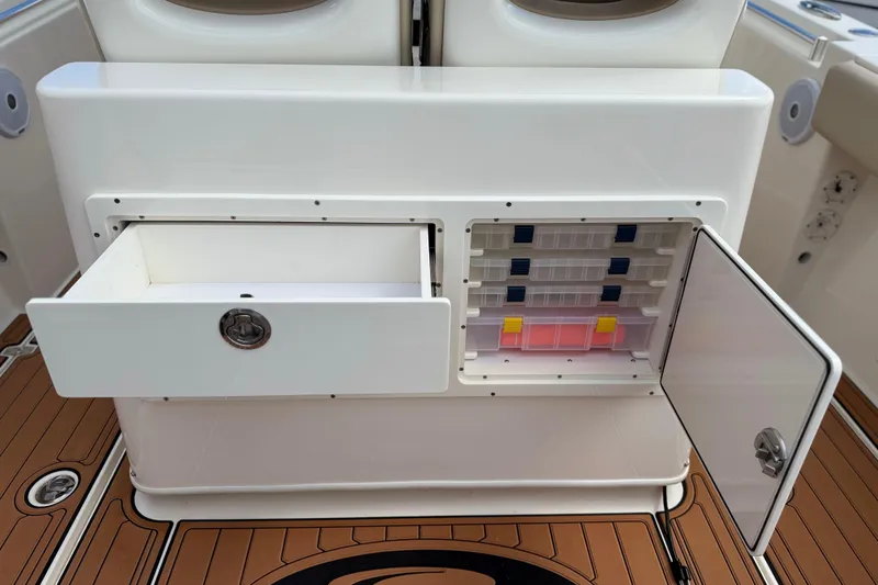 Slide: The Image of 2016 Cobia 277 Center Console storage compartments with open drawer and tackle box. - 23
