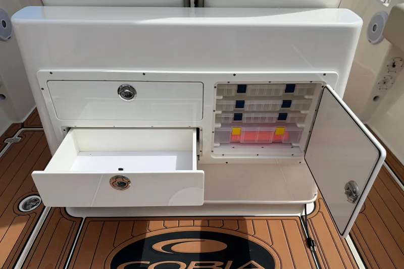 Slide: The Image of 2016 Cobia 277 Center Console storage compartments with open drawers and tackle box. - 24