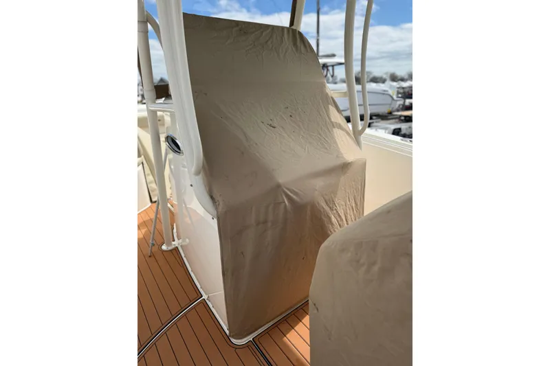 Slide: The Image of 2016 Cobia 277 Center Console helm covered, showcasing teak deck and protective cover. - 45