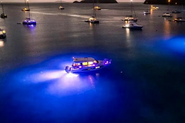 Slide: The Image of 2022 Regal 42 XO yacht illuminated at night on calm waters, surrounded by other boats. - 15