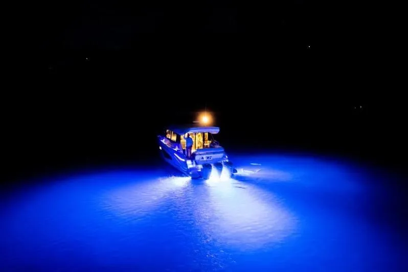 Slide: The Image of 2022 Regal 42 XO yacht illuminated by blue underwater lights at night. - 16