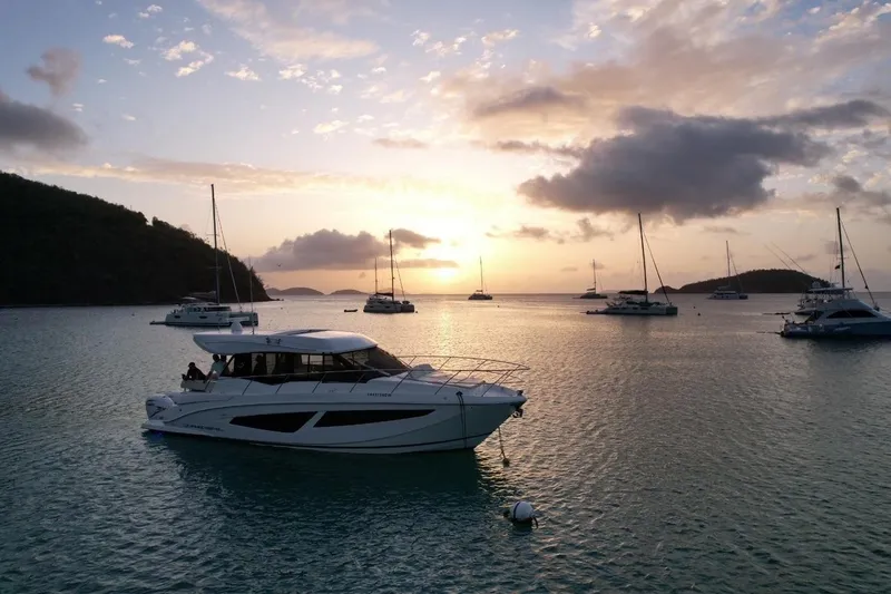 Slide: The Image of 2022 Regal 42 XO yacht at sunset, anchored in a serene bay with sailboats. - 6
