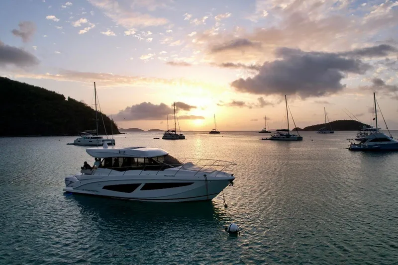 Slide: The Image of 2022 Regal 42 XO yacht at sunset, anchored in a serene bay with sailboats. - 7