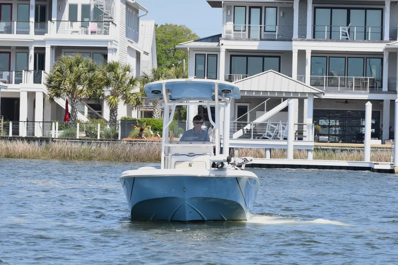Slide: The Image of 2022 Carolina Skiff 21 Ultra Elite boat cruising near waterfront homes. - 2