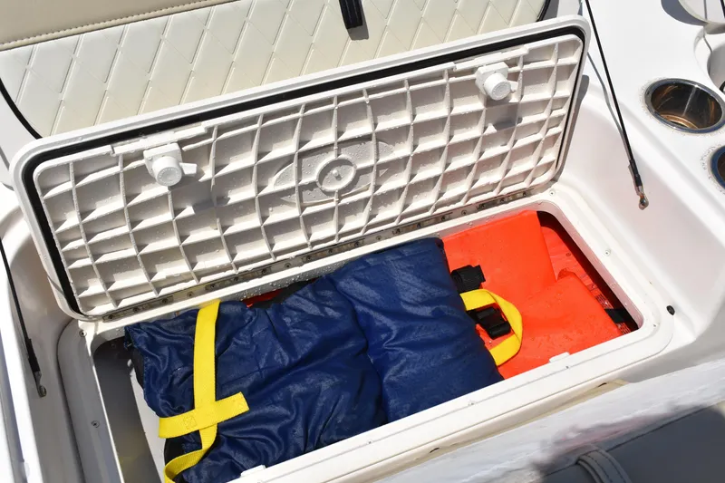 Slide: The Image of Open storage compartment on 2022 Carolina Skiff 21 Ultra Elite boat with life jackets inside. - 22