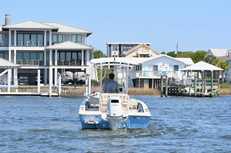 Slide: The Image of 2022 Carolina Skiff 21 Ultra Elite boat cruising near waterfront homes. - 5