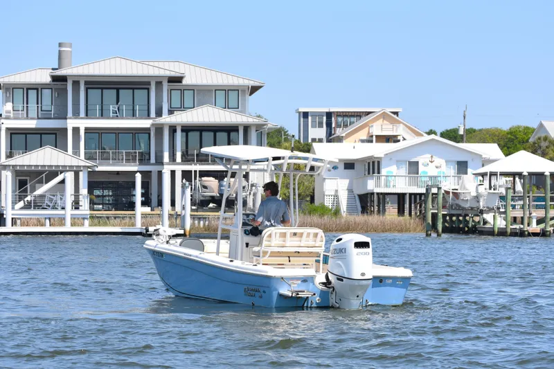 Slide: The Image of 2022 Carolina Skiff 21 Ultra Elite boat cruising near waterfront homes. - 6