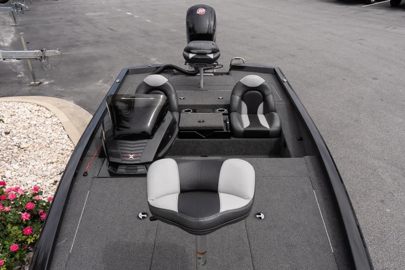 Slide: The Image of 2023 Vexus AVX1880 boat interior with seating and console, parked on pavement. - 10