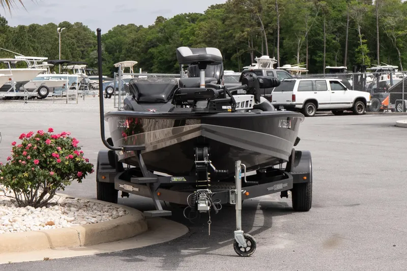 Slide: The Image of 2023 Vexus AVX1880 boat on trailer in parking lot with surrounding greenery. - 3