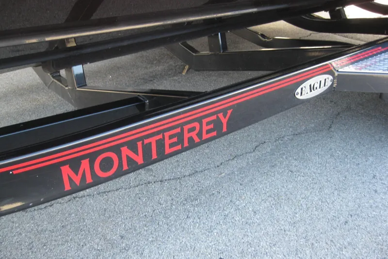 Slide: The Image of 2014 Monterey M3 Sport Boat trailer with red branding on pavement. - 37
