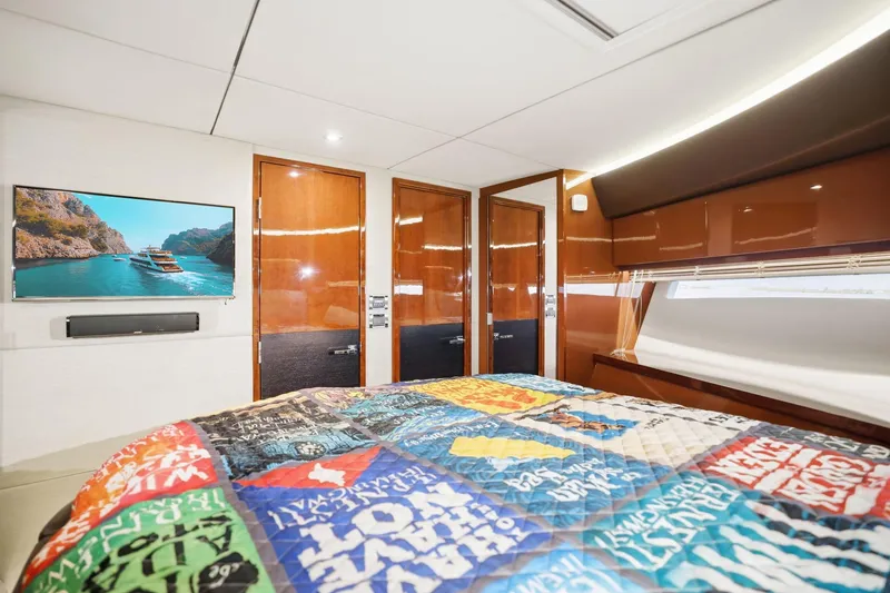 Slide: The Image of Luxurious 2017 Sea Ray L590 yacht bedroom with vibrant quilt and wall-mounted TV. - 103