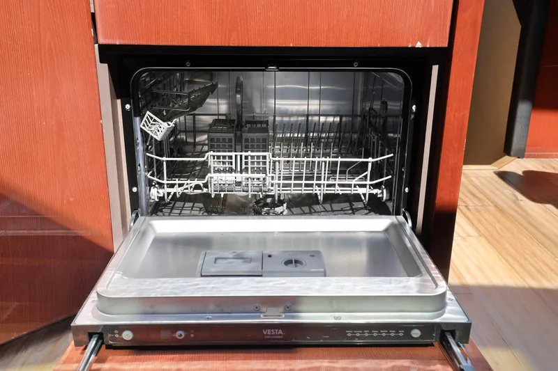 Slide: The Image of Open dishwasher inside 2017 Sea Ray L590 yacht, showcasing interior racks and controls. - 107