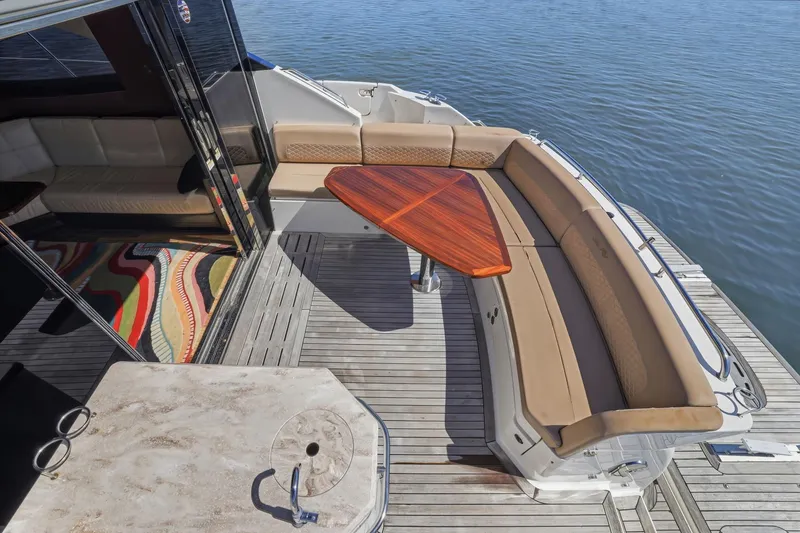 Slide: The Image of Luxurious 2017 Sea Ray L590 yacht deck with elegant seating and wooden table by the water. - 84