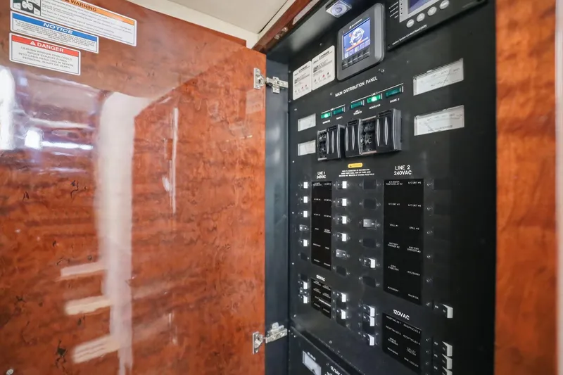 Slide: The Image of Electrical panel inside 2017 Sea Ray L590 yacht, featuring control switches and warning labels. - 97