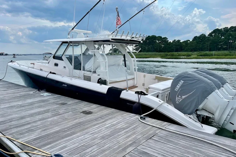 Slide: The Image of 2019 Pursuit S 408 Sport boat docked, featuring Yamaha engines, under a cloudy sky. - 2