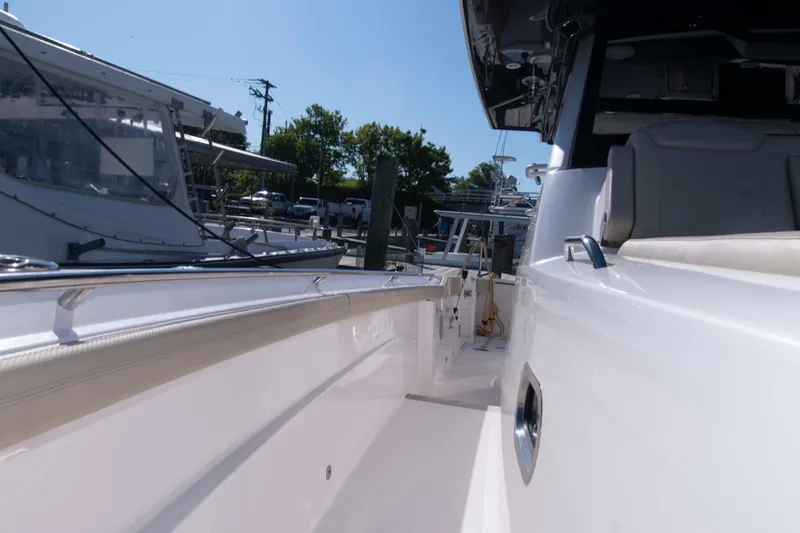 Slide: The Image of 2019 Pursuit S 408 Sport boat docked, showcasing sleek white exterior and seating area. - 23