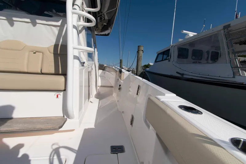 Slide: The Image of 2019 Pursuit S 408 Sport boat interior with beige seating, docked beside another vessel. - 24