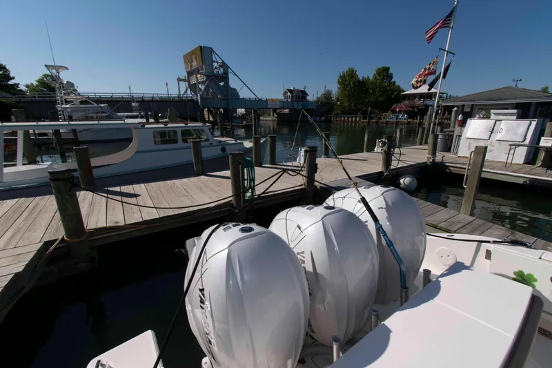 Slide: The Image of 2019 Pursuit S 408 Sport boat docked at a marina with triple outboard engines. - 27