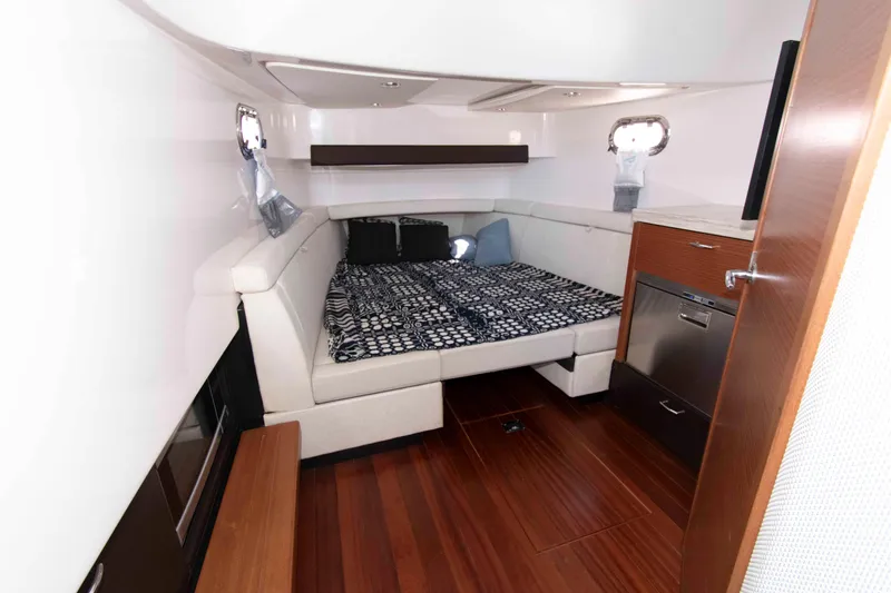 Slide: The Image of 2019 Pursuit S 408 Sport cabin interior with bed, wood flooring, and compact kitchenette. - 30
