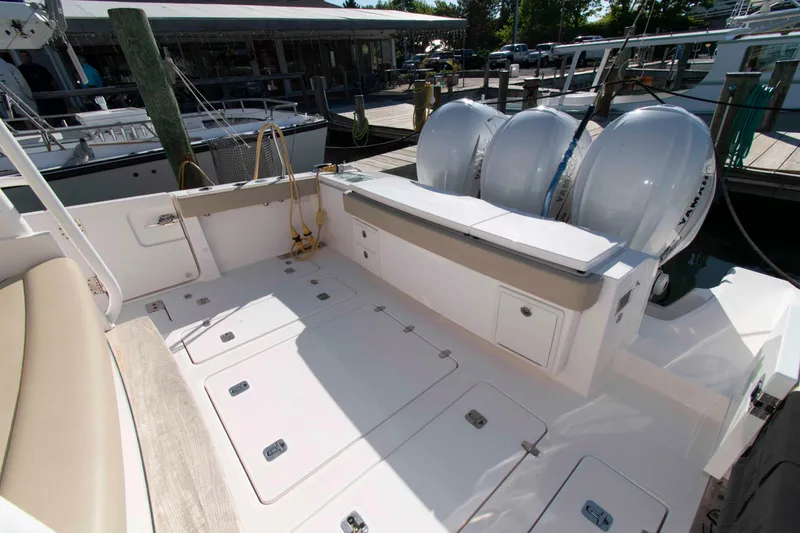 Slide: The Image of 2019 Pursuit S 408 Sport boat deck with triple outboard engines at a marina. - 8