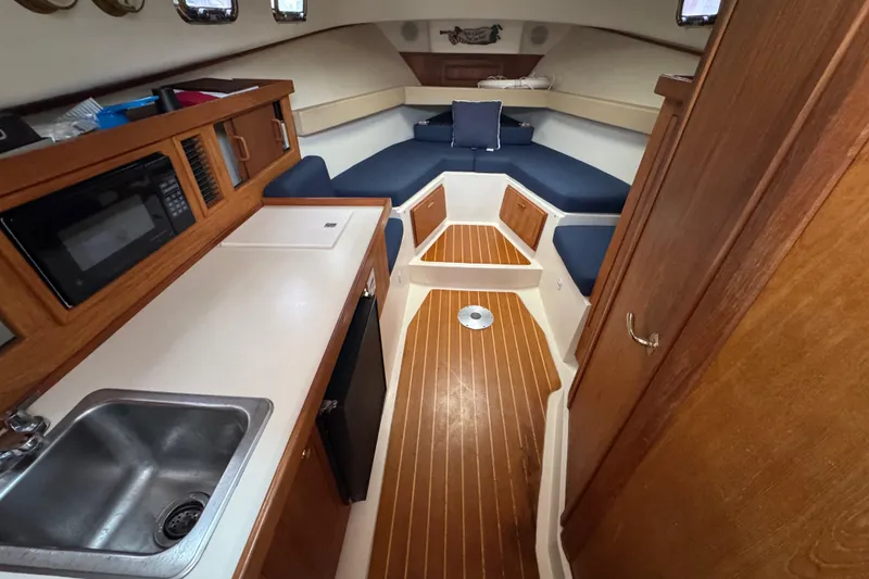 Slide: The Image of 2001 Mainship Pilot 30 interior with kitchenette, sink, and cozy seating area. - 10