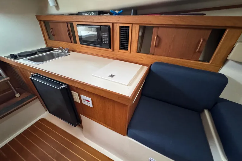 Slide: The Image of 2001 Mainship Pilot 30 galley with sink, microwave, and seating area. - 12