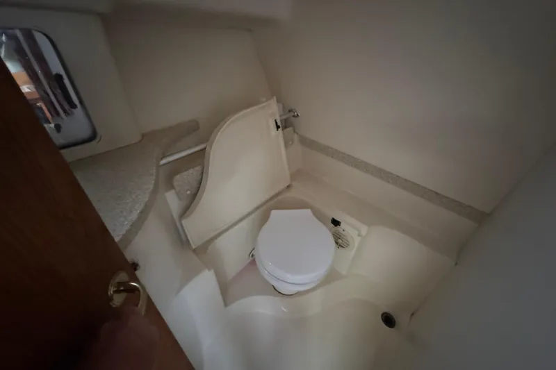 Slide: The Image of Compact bathroom in a 2001 Mainship Pilot 30 boat, featuring a toilet and small sink. - 14