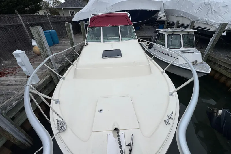 Slide: The Image of 2001 Mainship Pilot 30 docked, featuring a spacious deck and red canopy. - 4