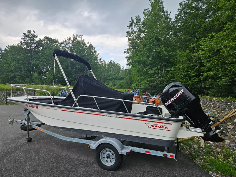Slide: The Image of 2008 Boston Whaler 170 Montauk boat on trailer, parked near lush green trees. - 2