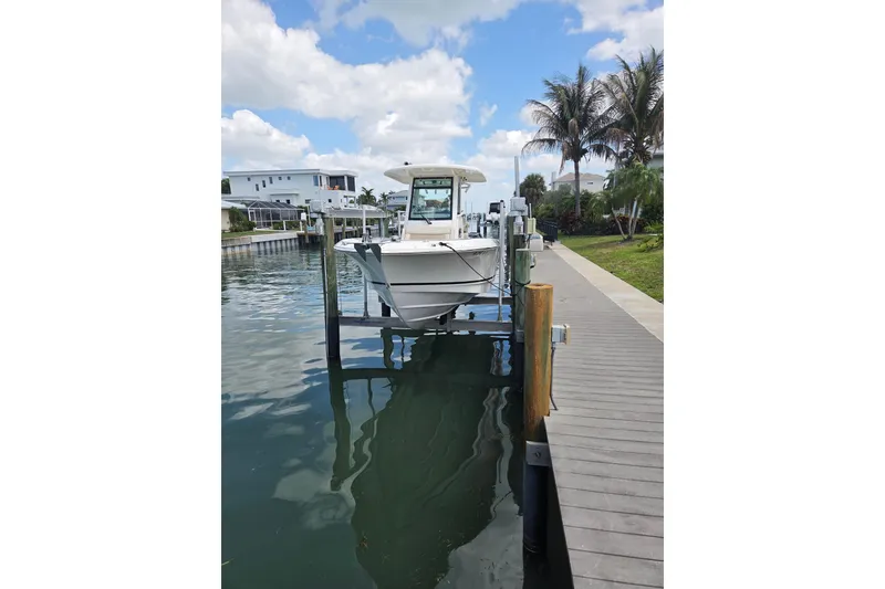 Slide: The Image of 2017 Boston Whaler 250 Outrage boat docked on a lift by a waterfront home. - 20