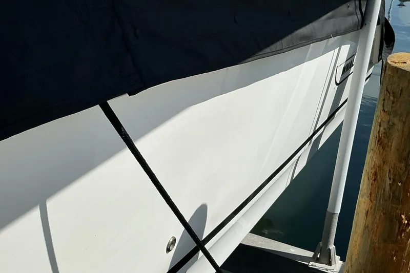 Slide: The Image of 2017 Boston Whaler 250 Outrage boat docked, partially covered, with visible hull and mooring lines. - 22