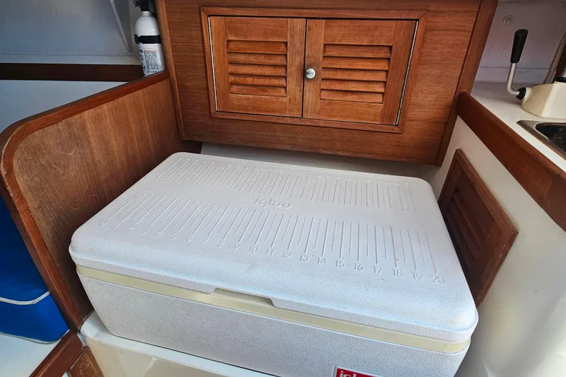 Slide: The Image of Wooden interior of 2003 Herreshoff Alerion 26 with Igloo cooler and storage cabinet. - 10