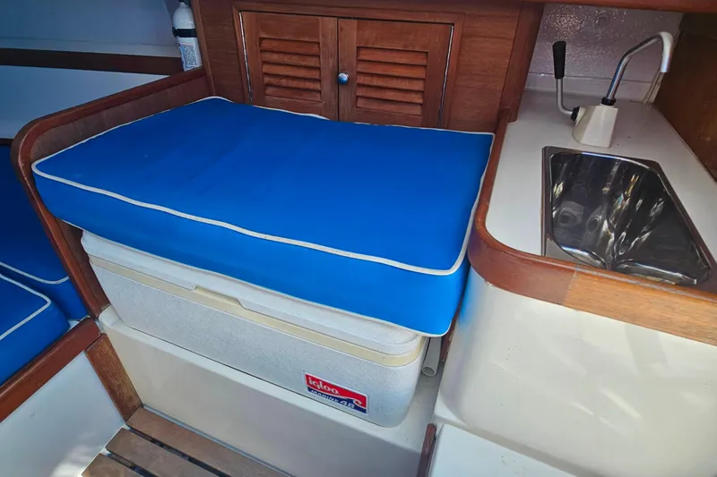 Slide: The Image of Interior of 2003 Herreshoff Alerion 26 with blue cushioned seating and compact sink. - 12