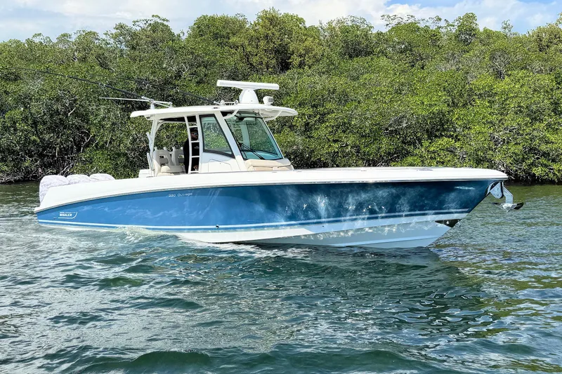 The Image of 2019 Boston Whaler 350 Outrage boat cruising on water near lush greenery. - 0