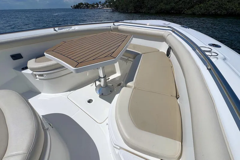 Slide: The Image of 2019 Boston Whaler 350 Outrage boat interior with seating and table, near water. - 14