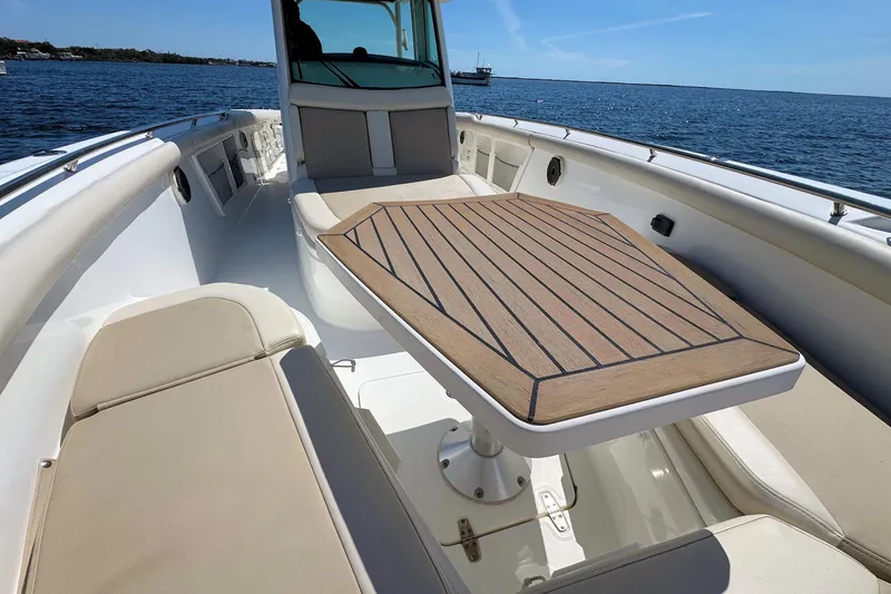 Slide: The Image of 2019 Boston Whaler 350 Outrage boat interior with wooden table and seating, on open water. - 15