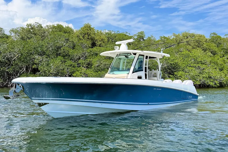 Slide: The Image of 2019 Boston Whaler 350 Outrage boat on water near lush greenery. - 2