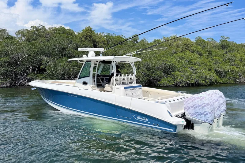 Slide: The Image of 2019 Boston Whaler 350 Outrage boat cruising on water near lush greenery. - 4