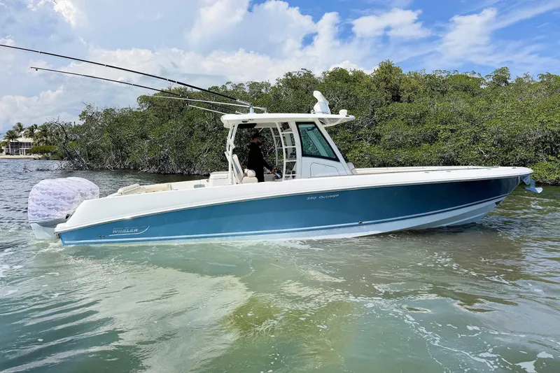 Slide: The Image of 2019 Boston Whaler 350 Outrage boat cruising on calm waters near lush greenery. - 5
