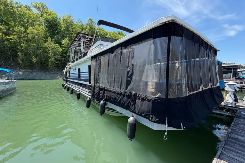 The Image of 1989 Sumerset 14x62 houseboat docked on a sunny day with lush greenery. - 0