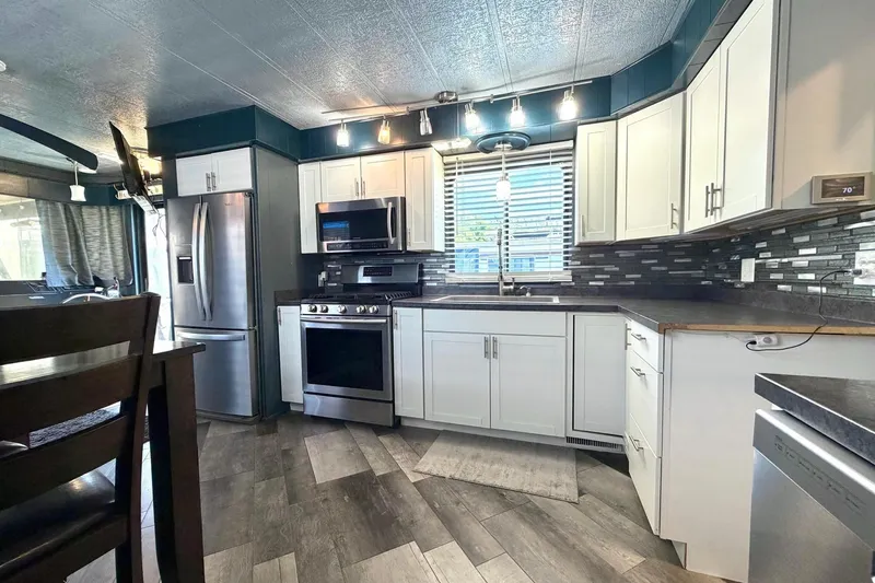 Slide: The Image of Modern kitchen in a 1989 Sumerset 14x62 houseboat with stainless steel appliances and white cabinetry. - 10