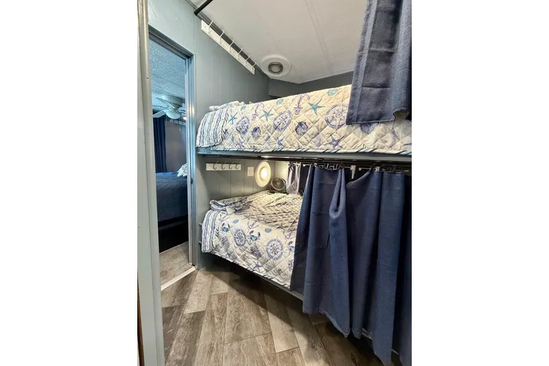 Slide: The Image of Bunk beds in a 1989 Sumerset 14x62 houseboat with nautical-themed bedding and blue curtains. - 14